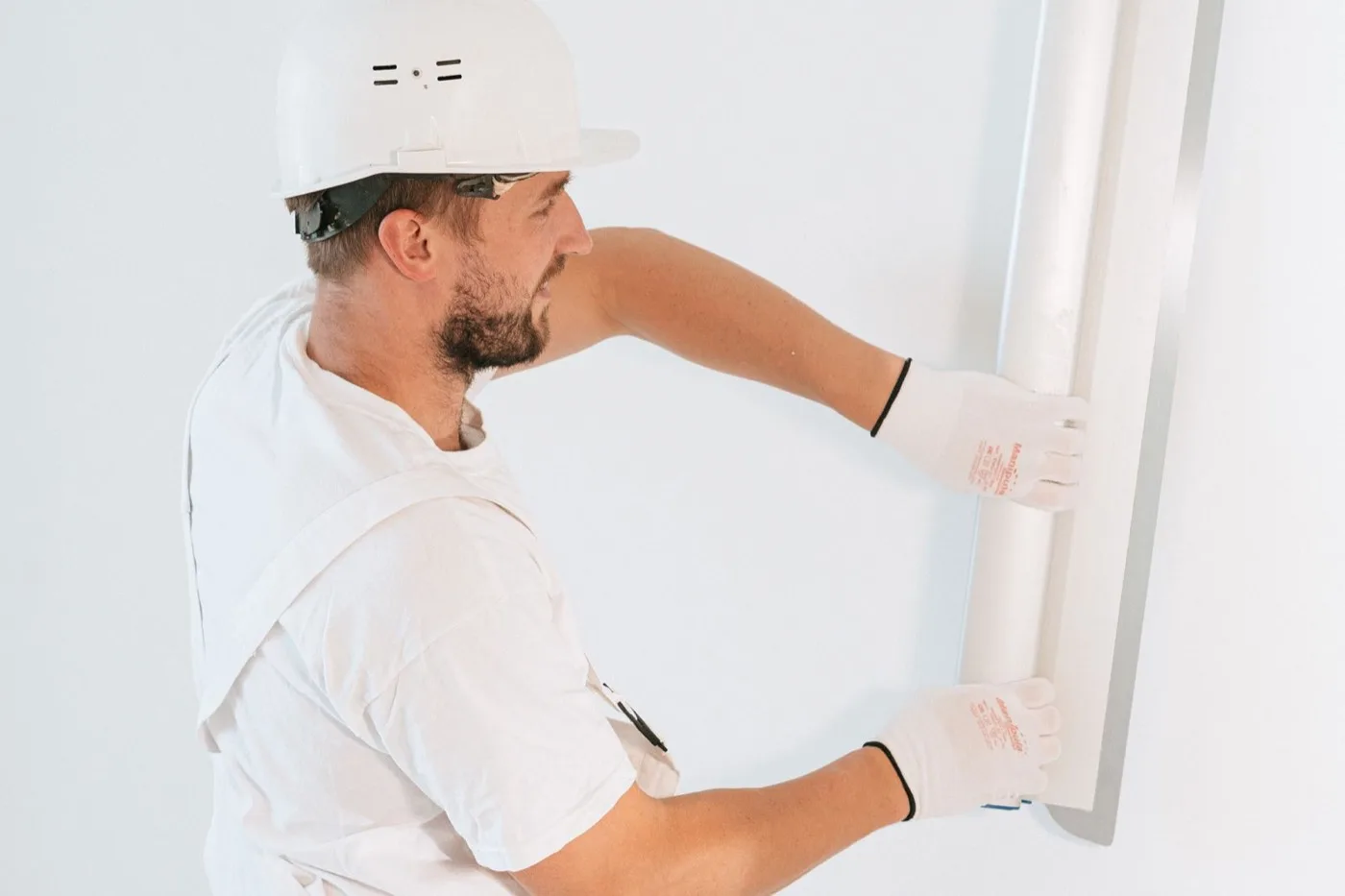 Operario con casco y guantes colocando una placa en una pared blanca